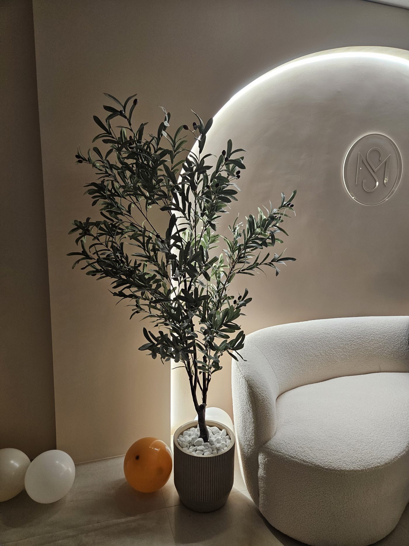 De verlichte boog met het MS-logo en de witte fauteuil in Melana Studio